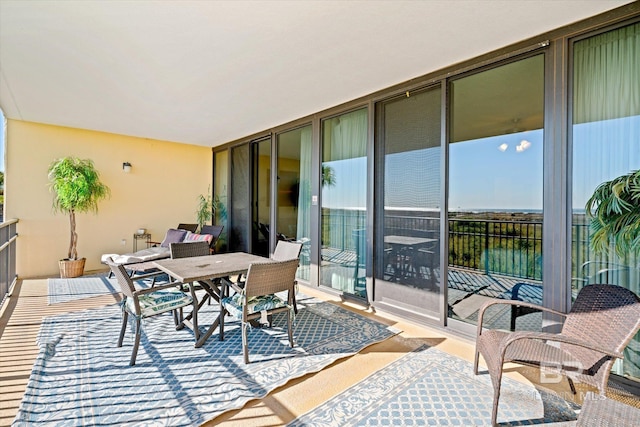 balcony featuring a sunroom and outdoor dining area