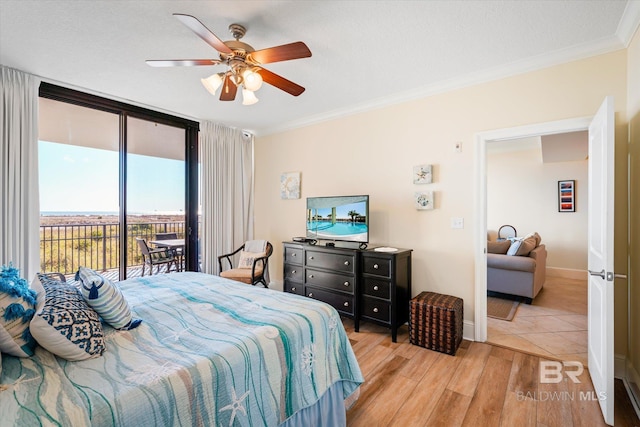 bedroom featuring access to exterior, crown molding, a wall of windows, light wood-type flooring, and baseboards