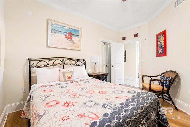 bedroom featuring baseboards, visible vents, crown molding, and wood finished floors