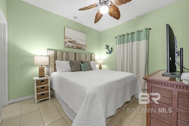 tiled bedroom featuring baseboards and a ceiling fan