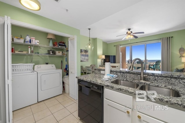 kitchen featuring a sink, black dishwasher, white cabinetry, light stone countertops, and washing machine and clothes dryer