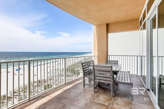 balcony with a view of the beach, a water view, and outdoor dining space