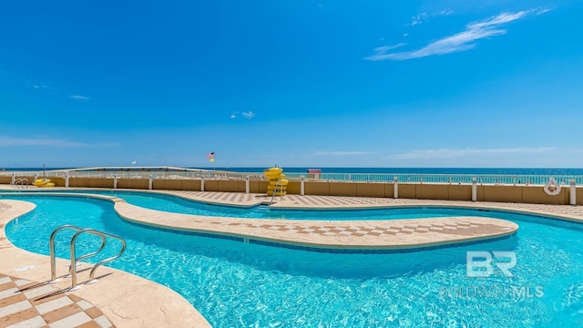 community pool featuring a water view and fence