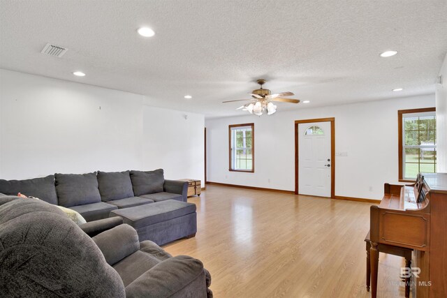 living room with a textured ceiling, ceiling fan, and light hardwood / wood-style floors