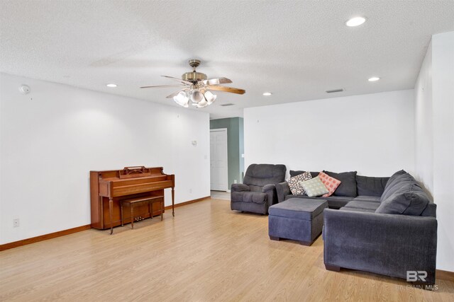 living room featuring a textured ceiling, ceiling fan, and light wood-type flooring