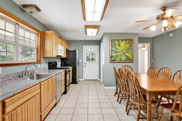 kitchen featuring light brown cabinetry, sink, ceiling fan, stainless steel dishwasher, and range