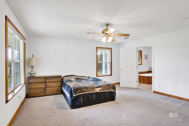 carpeted bedroom featuring a textured ceiling, ceiling fan, and ensuite bath