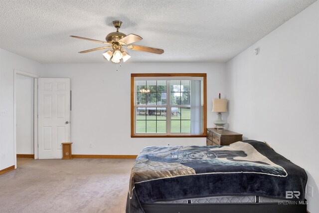 bedroom with ceiling fan, light carpet, and a textured ceiling