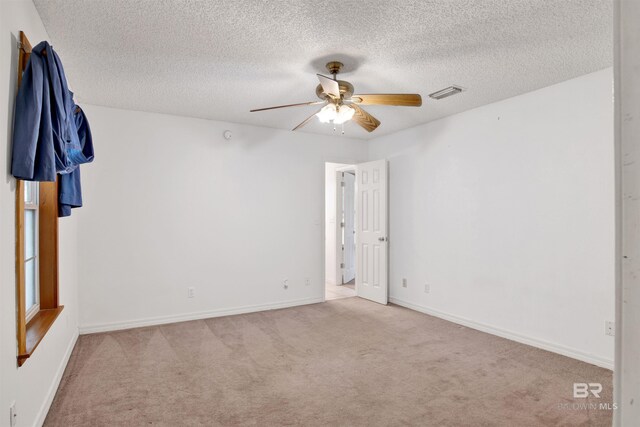 unfurnished room with ceiling fan, light carpet, and a textured ceiling