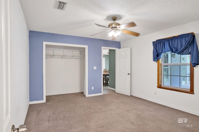 unfurnished bedroom featuring light carpet, a textured ceiling, ceiling fan, and a closet