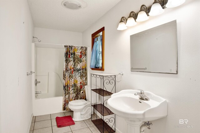 full bathroom featuring tile patterned flooring, toilet, sink, shower / bath combo with shower curtain, and a textured ceiling