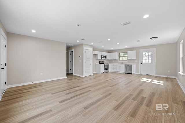 unfurnished living room featuring light wood finished floors, baseboards, visible vents, and recessed lighting