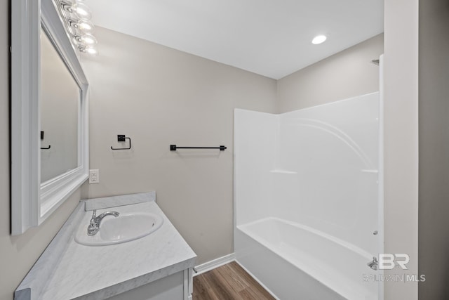 bathroom with tub / shower combination, vanity, baseboards, and wood finished floors