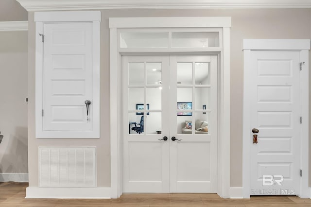 interior space featuring visible vents, ornamental molding, light wood-style flooring, and baseboards