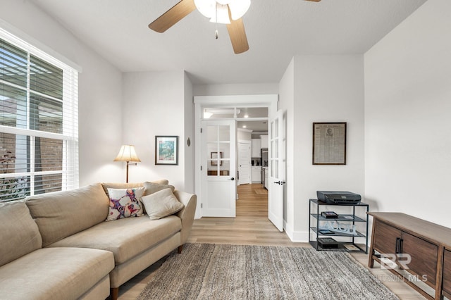 living room featuring baseboards, ceiling fan, and wood finished floors