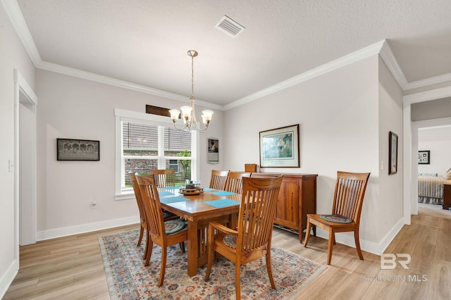 dining space featuring visible vents, ornamental molding, an inviting chandelier, baseboards, and light wood finished floors