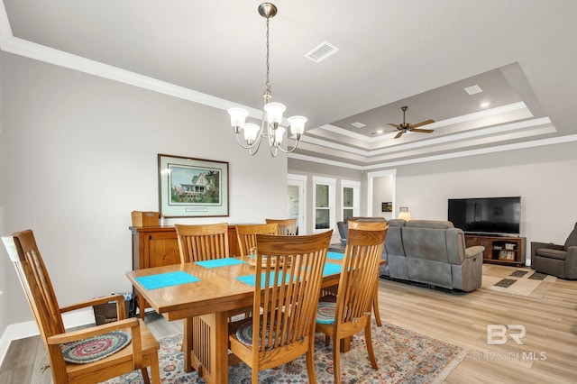 dining room with crown molding, a raised ceiling, visible vents, and ceiling fan with notable chandelier
