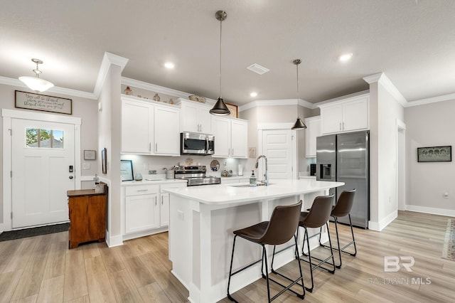 kitchen with crown molding, a sink, stainless steel appliances, white cabinetry, and visible vents