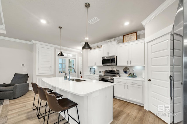 kitchen with stainless steel appliances, ornamental molding, a sink, and light wood finished floors
