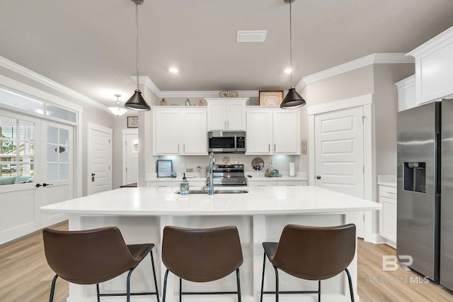 kitchen featuring a breakfast bar, light countertops, stainless steel appliances, visible vents, and ornamental molding