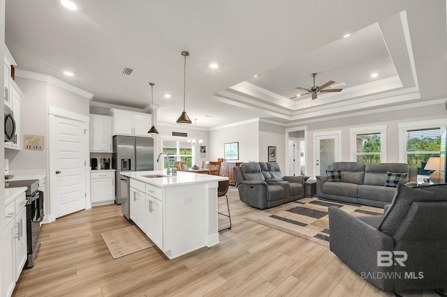 kitchen featuring a sink, light countertops, stainless steel appliances, open floor plan, and a ceiling fan