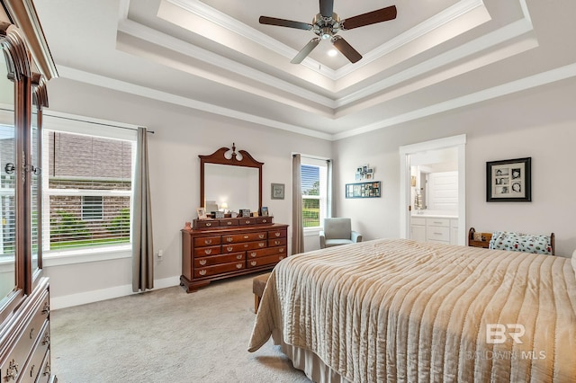 bedroom with crown molding, baseboards, light carpet, a tray ceiling, and ensuite bath