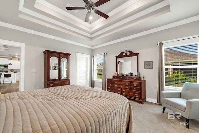bedroom with a ceiling fan, a tray ceiling, light colored carpet, and ornamental molding