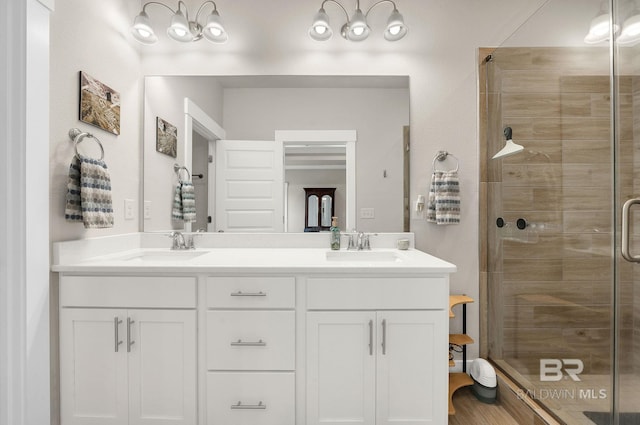 bathroom with a sink, a stall shower, and double vanity
