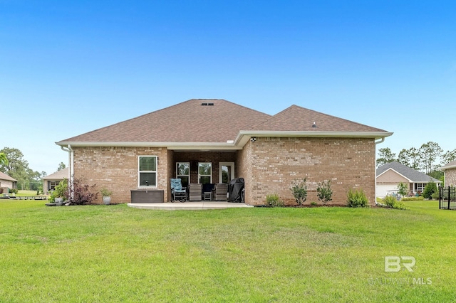 back of house featuring a lawn, brick siding, a patio area, and roof with shingles