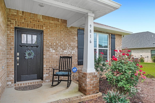 property entrance featuring covered porch and brick siding