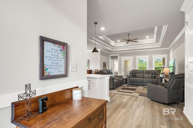 living area with crown molding, recessed lighting, a raised ceiling, a ceiling fan, and light wood finished floors