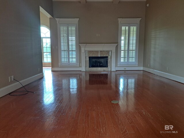 living room with beamed ceiling, wood-type flooring, ceiling fan, ornamental molding, and a premium fireplace