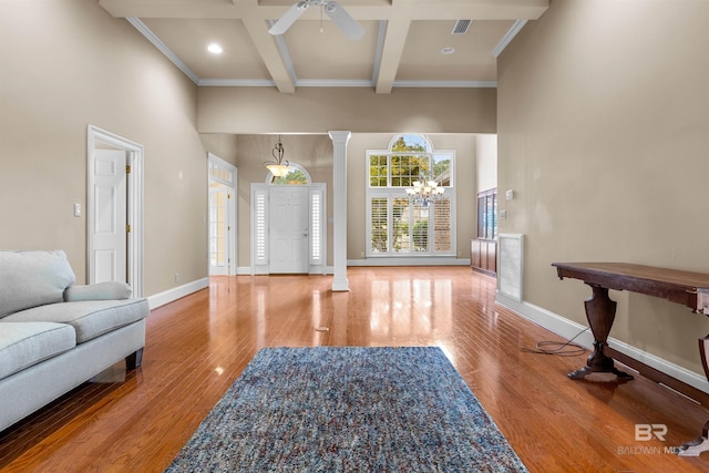 living room with ceiling fan with notable chandelier, beam ceiling, hardwood / wood-style floors, and ornate columns