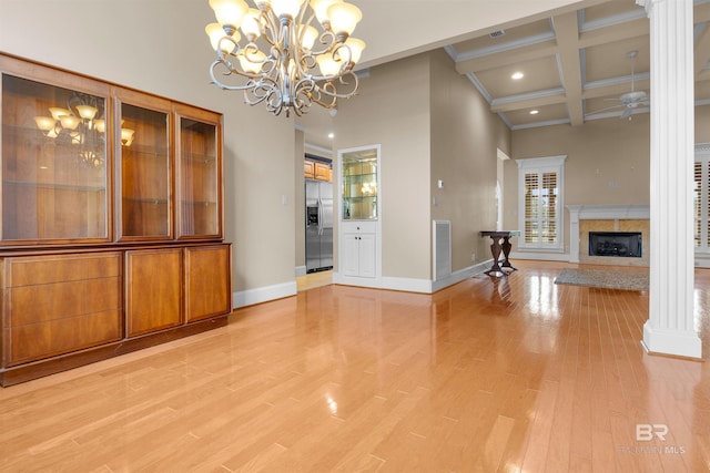 unfurnished dining area with decorative columns, light hardwood / wood-style floors, beamed ceiling, and a premium fireplace