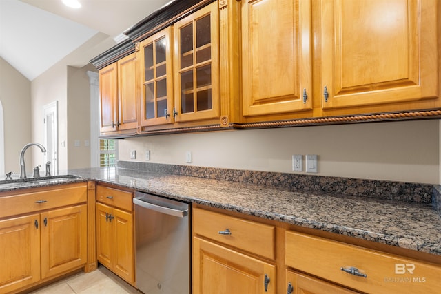 kitchen with dark stone countertops, vaulted ceiling, sink, and stainless steel dishwasher