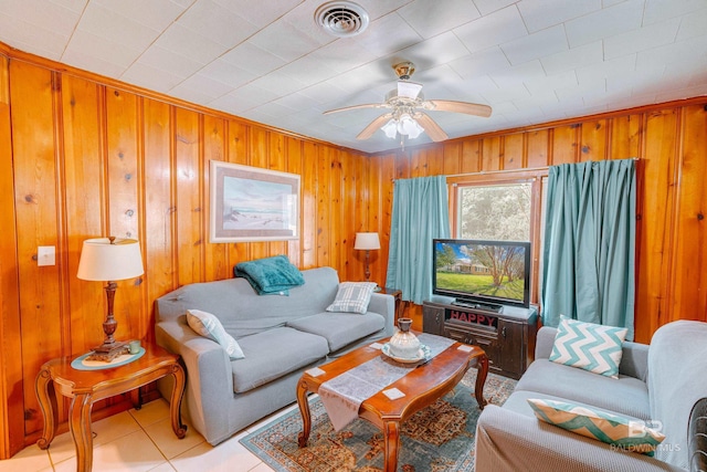 living room with wooden walls, light tile patterned floors, and ceiling fan