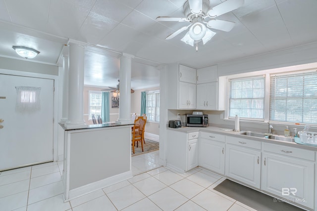 kitchen with white cabinets, light tile patterned floors, decorative columns, and a healthy amount of sunlight