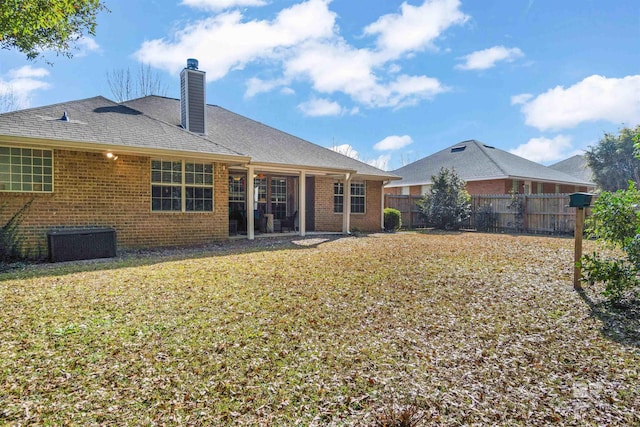 rear view of property with central AC unit and a lawn