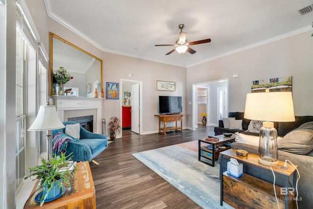 living room featuring dark hardwood / wood-style flooring, ornamental molding, a tile fireplace, and ceiling fan