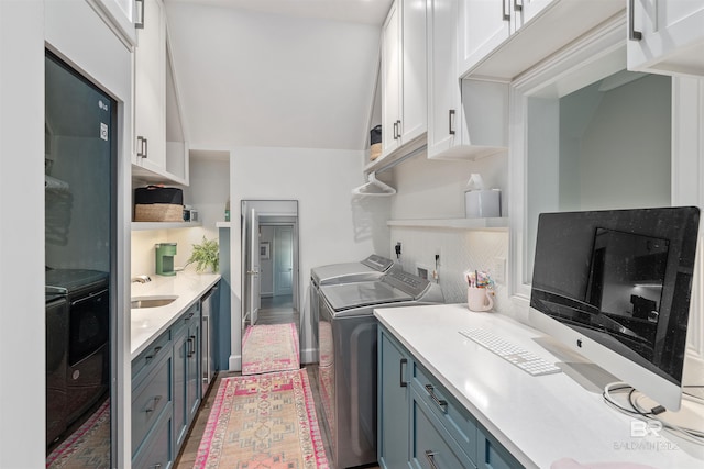 kitchen featuring sink, blue cabinets, washing machine and clothes dryer, black fridge, and white cabinets