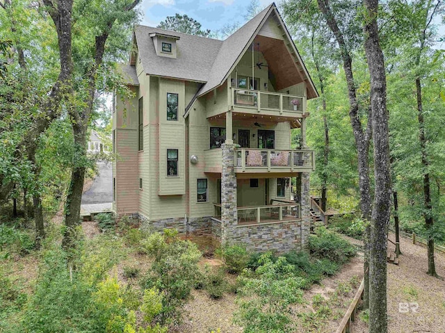 rear view of house featuring ceiling fan and a balcony