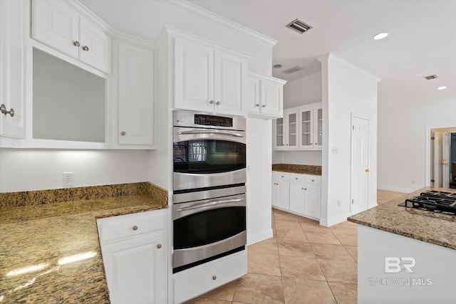 kitchen featuring black gas stovetop, white cabinets, double oven, and dark stone counters