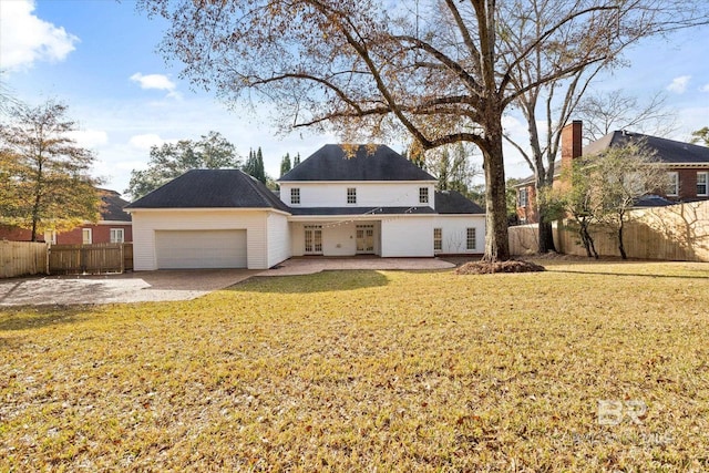 back of property with a garage and a lawn