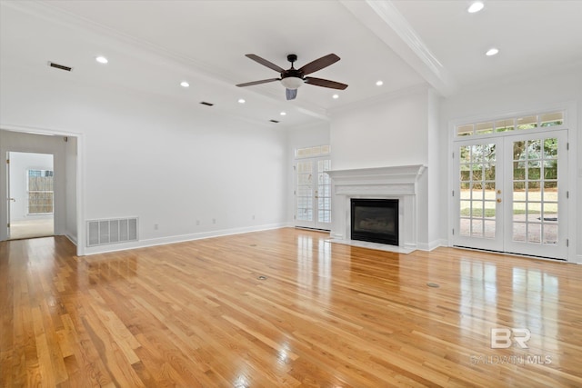 unfurnished living room featuring french doors, crown molding, light wood-type flooring, ceiling fan, and beam ceiling