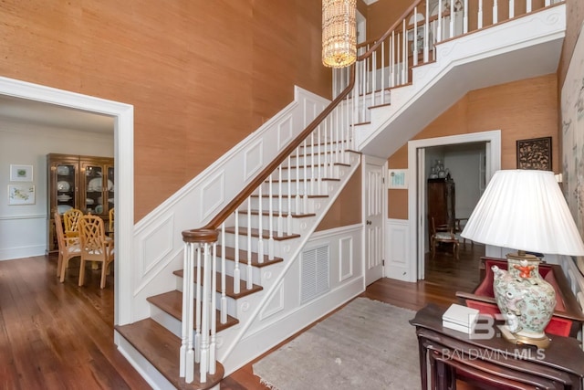41 Yester Pl, Mobile, AL 36608 - staircase with wood finished floors, a decorative wall, visible vents, a notable chandelier, and a towering ceiling