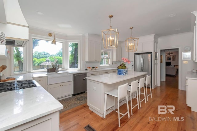 41 Yester Pl, Mobile, AL 36608 - kitchen featuring a breakfast bar area, light wood-style flooring, a sink, stainless steel appliances, and an inviting chandelier