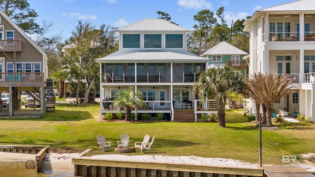 rear view of property featuring a lawn, a fire pit, metal roof, ceiling fan, and stairs