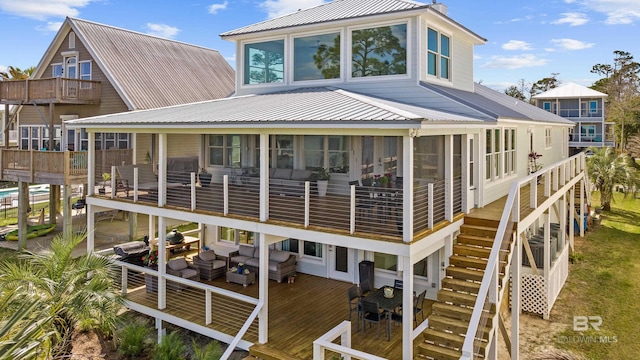rear view of property with a wooden deck, metal roof, stairs, and a sunroom