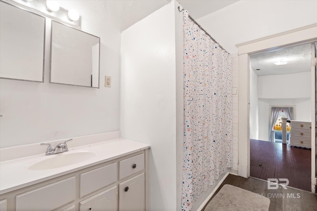 bathroom with walk in shower, vanity, and hardwood / wood-style floors