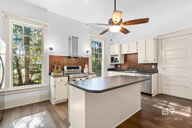 kitchen featuring tasteful backsplash, stainless steel appliances, island range hood, and white cabinets